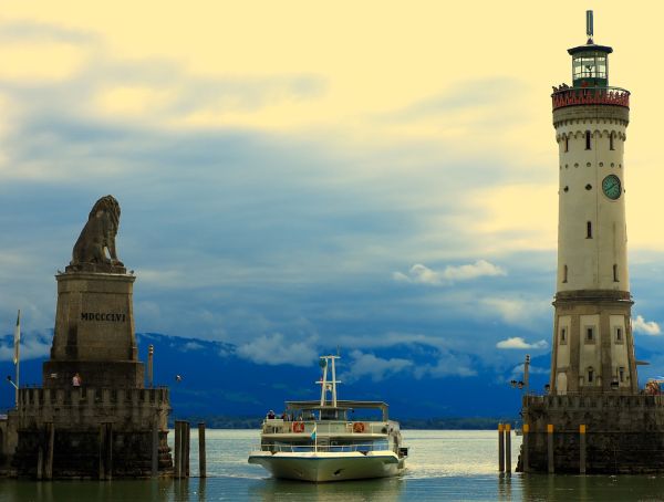 Foto Ansicht Bodensee: Hafeneinfahrt Lindau mit Löwe und Neuer Leuchtturm, im Hintergrund die Alpen