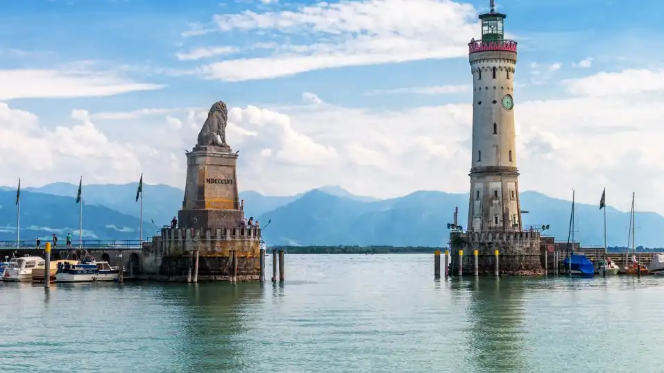 Ansicht Bodensee: Hafeneinfahrt Lindau mit Löwe und Neuer Leuchtturm, im Hintergrund die Alpen