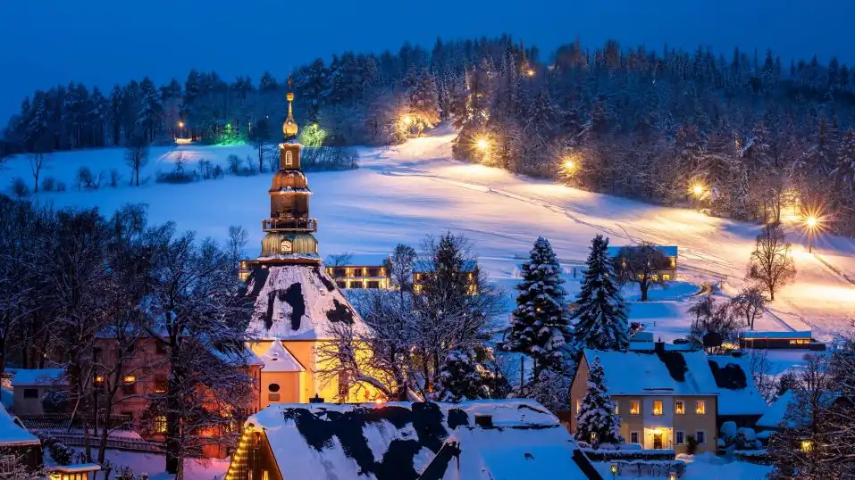 Kurort Seiffen im Erzgebirge mit Schnee- & Waldlandschaft, beleuchtet bei Nacht