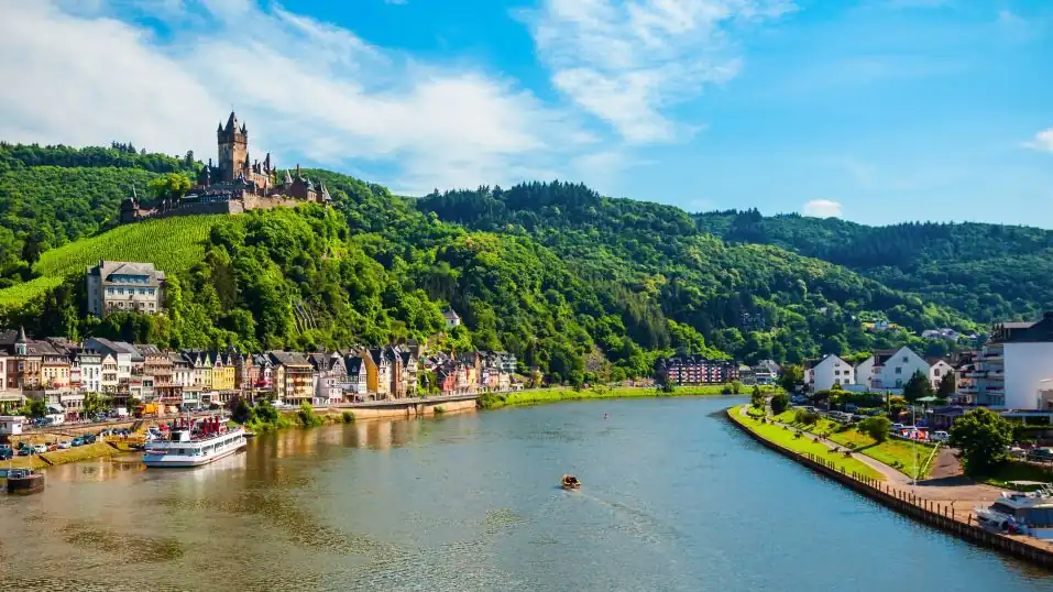 die Mosel bei Cochem - am Ufer die Stadt, darüber die bekannte Reichsburg, ein Schiff auf dem Fluss