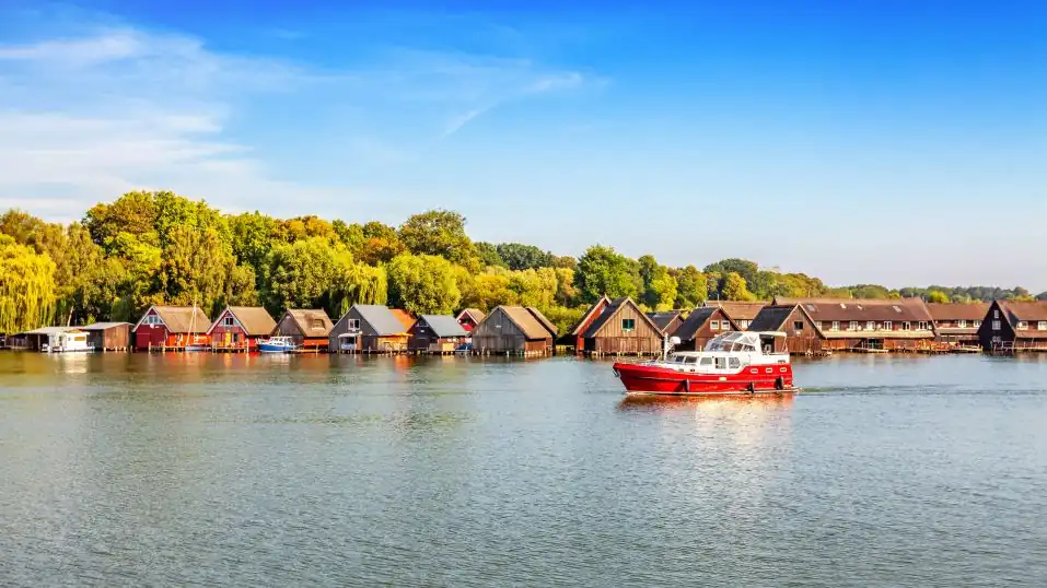 Röbel an der Müritz - Blick über den See, Holzhäuser im Wasser, davor ein Boot