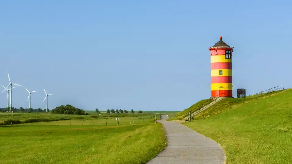 Landschaft in Ostfriesland bei Greetsiel, rechts der Pilsumer Leuchtturm, links Wiesen und Windräder