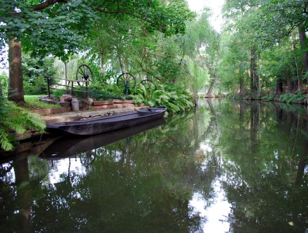 Foto Kanal im Spreewald, umgeben von Bäumen, links ein Kahn