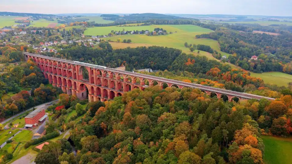 herbstliche Landsschaft im Vogtland, im Vordergrund die Göltzschtalbrücke, darauf ein Zug